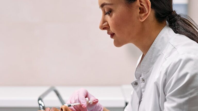 A female dermatologist applying a facial treatment to a patient in a medical clinic setting.