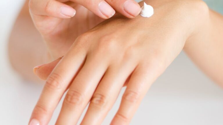 A woman applying cream on her hands, highlighting skincare and self-care concepts.