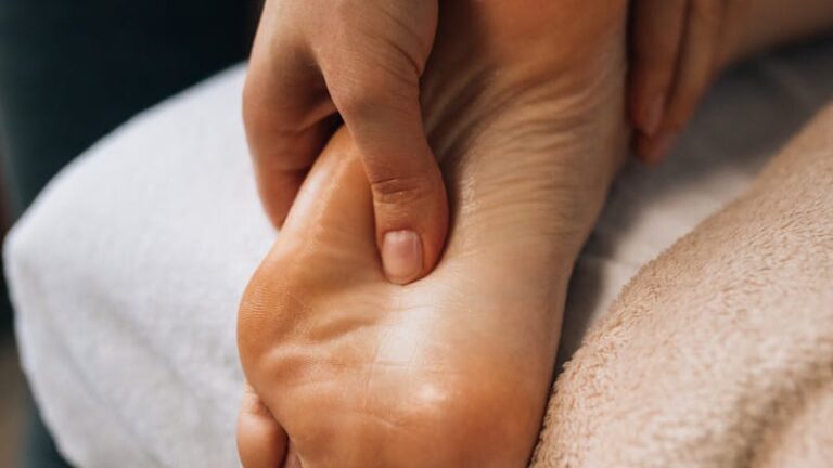 Hands massaging a foot to provide relaxation and promote wellness indoors.